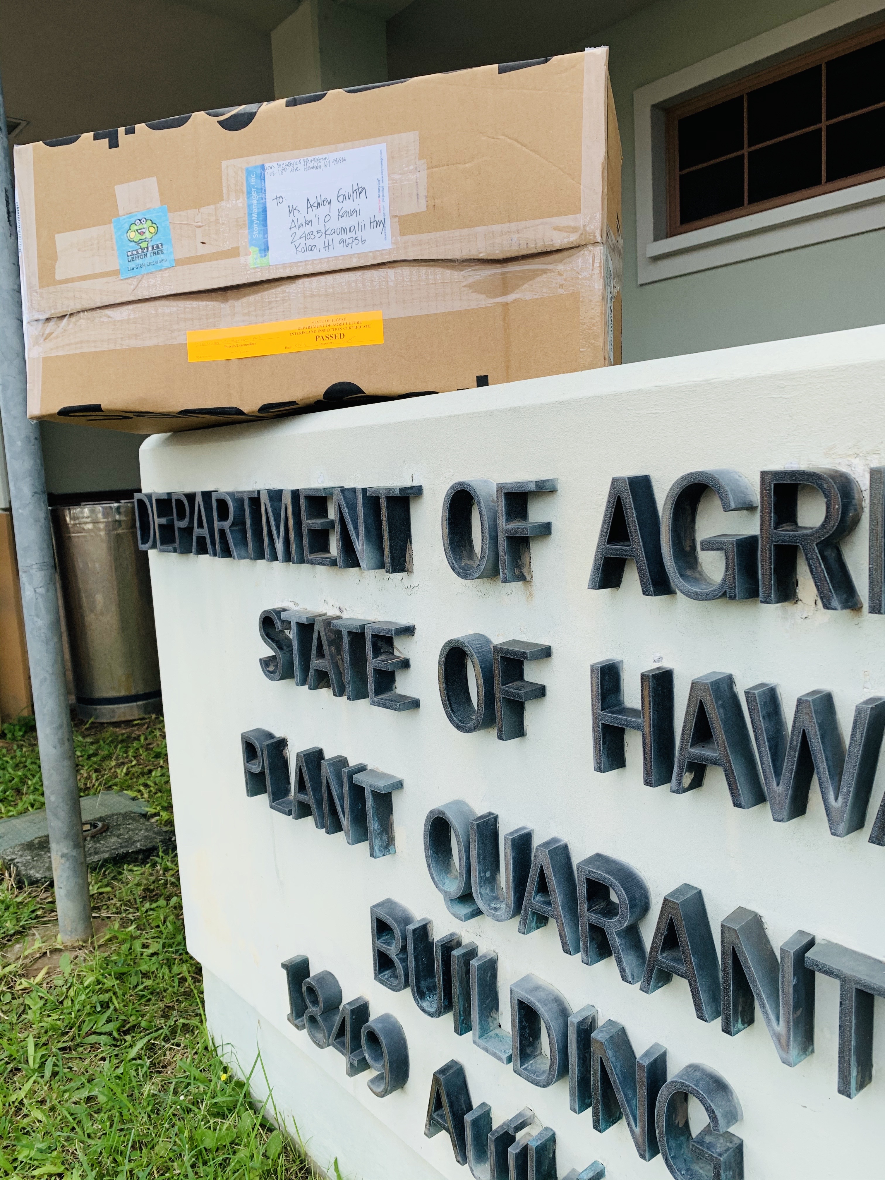Box of lemon trees above State of Hawaiʻi Department of Agriculture sign