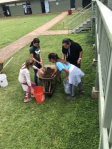6th grade students transfer soil from a wheelbarrow to a bucket